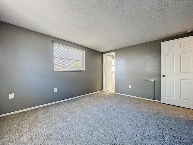 unfurnished room with baseboards, carpet floors, and a textured ceiling