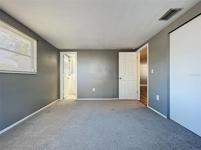 unfurnished bedroom with visible vents, carpet flooring, a textured ceiling, and baseboards