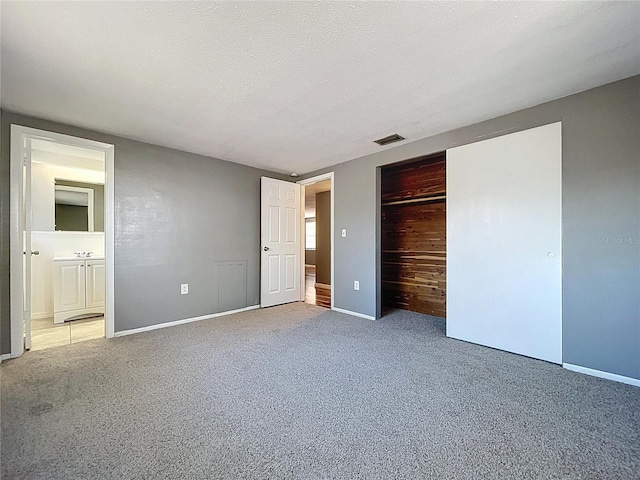 unfurnished bedroom featuring baseboards, a closet, carpet floors, and a textured ceiling