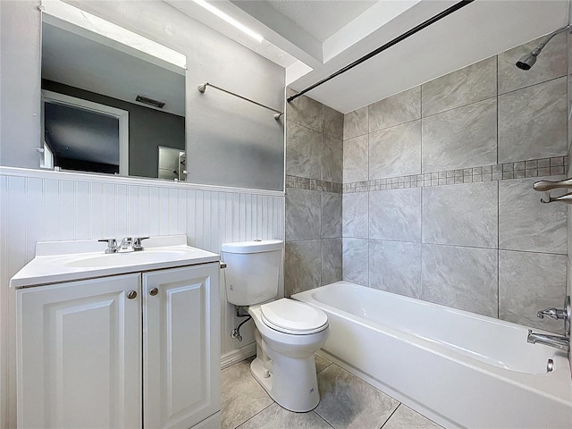 bathroom featuring tile patterned flooring, toilet, wainscoting, bathing tub / shower combination, and vanity