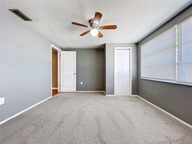 unfurnished bedroom with baseboards, visible vents, ceiling fan, a closet, and carpet flooring