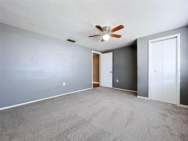 unfurnished bedroom with visible vents, a textured ceiling, carpet flooring, baseboards, and ceiling fan