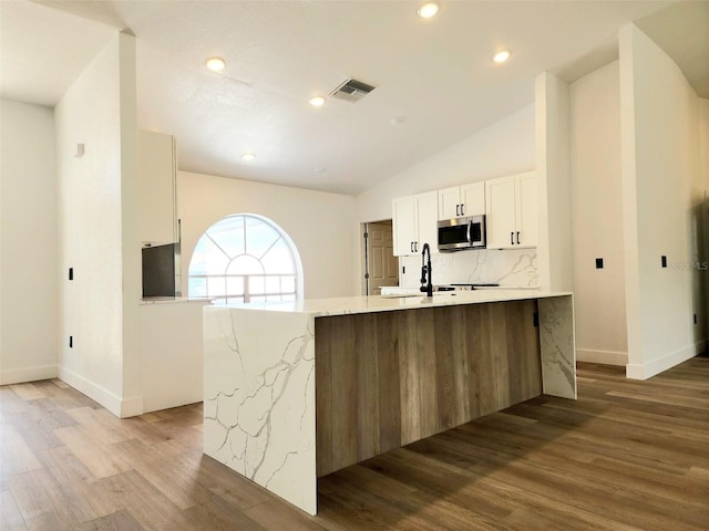 1032 Concert Ave, Spring Hill, FL 34609 - kitchen featuring visible vents, light wood-style flooring, stainless steel microwave, white cabinetry, and lofted ceiling
