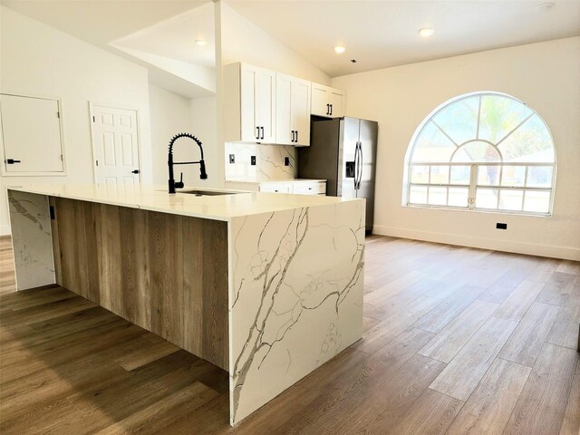 1032 Concert Ave, Spring Hill, FL 34609 - kitchen featuring a sink, wood finished floors, white cabinets, stainless steel fridge with ice dispenser, and lofted ceiling