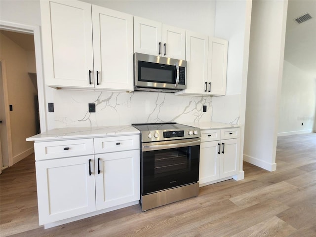 1032 Concert Ave, Spring Hill, FL 34609 - kitchen with visible vents, backsplash, appliances with stainless steel finishes, and light wood finished floors