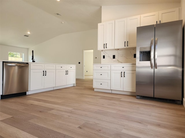 1032 Concert Ave, Spring Hill, FL 34609 - kitchen with lofted ceiling, light wood-style flooring, appliances with stainless steel finishes, white cabinetry, and backsplash
