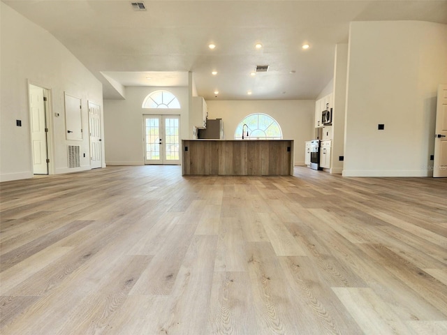 1032 Concert Ave, Spring Hill, FL 34609 - unfurnished living room with light wood-style flooring, french doors, and a high ceiling