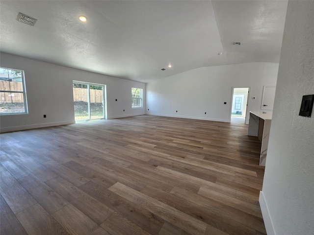 1032 Concert Ave, Spring Hill, FL 34609 - unfurnished living room featuring visible vents, lofted ceiling, baseboards, and wood finished floors