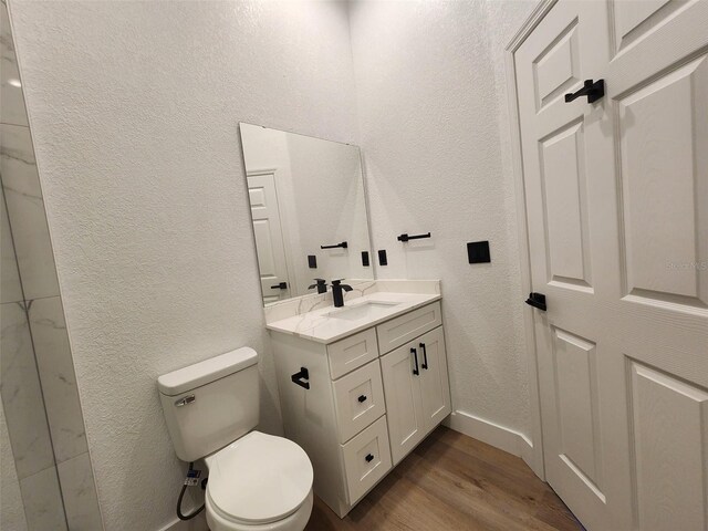 1032 Concert Ave, Spring Hill, FL 34609 - bathroom featuring baseboards, toilet, a textured wall, wood finished floors, and vanity