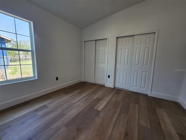 1032 Concert Ave, Spring Hill, FL 34609 - unfurnished bedroom with dark wood finished floors, lofted ceiling, baseboards, and two closets