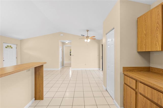 kitchen with baseboards, ceiling fan, light countertops, vaulted ceiling, and light tile patterned floors