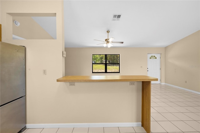 kitchen featuring a ceiling fan, visible vents, a peninsula, freestanding refrigerator, and light countertops