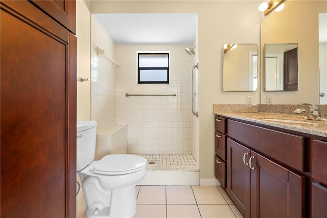 bathroom with vanity, toilet, a tile shower, and tile patterned flooring