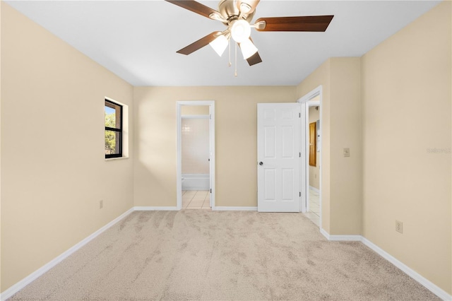 unfurnished bedroom featuring ceiling fan, baseboards, ensuite bathroom, and light carpet