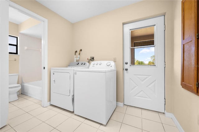 laundry area featuring laundry area, light tile patterned floors, separate washer and dryer, and baseboards