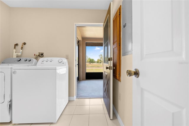 clothes washing area featuring laundry area, light tile patterned floors, baseboards, and washer and clothes dryer