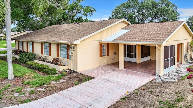 view of front of property featuring stucco siding, a shingled roof, and a sunroom