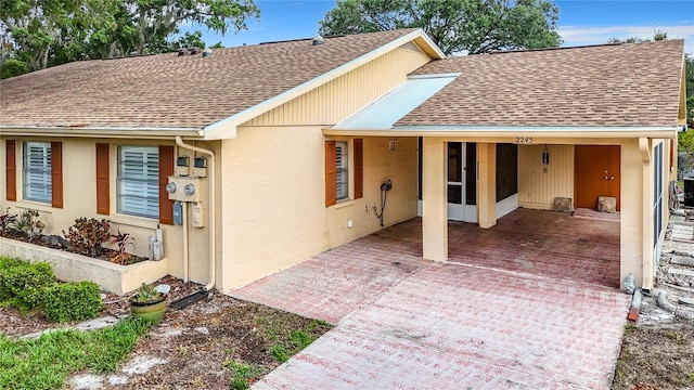 exterior space with stucco siding and roof with shingles