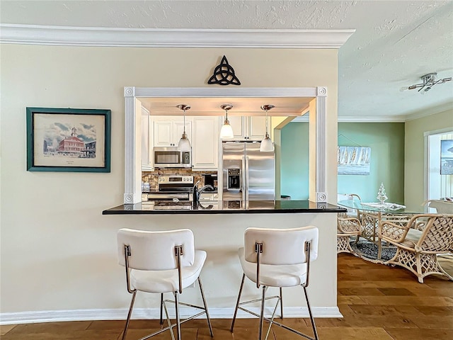 kitchen featuring dark countertops, wood finished floors, stainless steel appliances, and ornamental molding