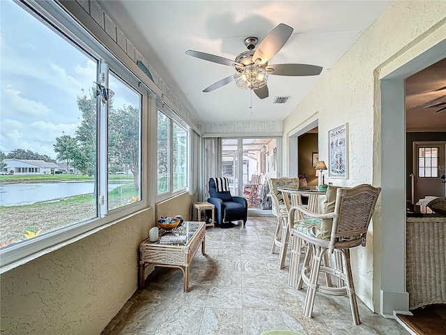 sunroom featuring visible vents, a water view, and ceiling fan