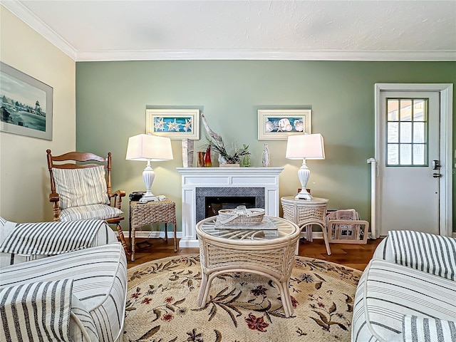 living area with baseboards, wood finished floors, a fireplace, and crown molding