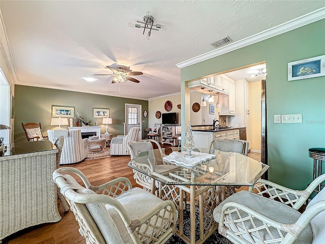 dining room featuring crown molding, wood finished floors, visible vents, and ceiling fan