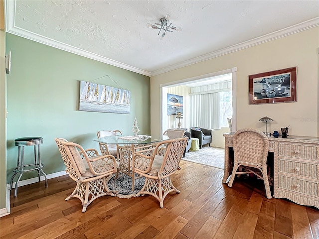 dining area with a textured ceiling, baseboards, wood-type flooring, and ornamental molding