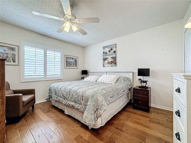 bedroom with a textured ceiling, a ceiling fan, baseboards, and hardwood / wood-style floors