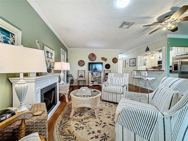 living room featuring visible vents, crown molding, a ceiling fan, and wood finished floors