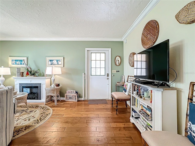 living area featuring a fireplace, a textured ceiling, crown molding, and hardwood / wood-style floors