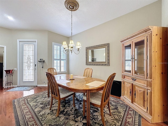 dining room with a chandelier, a textured ceiling, light wood-type flooring, and baseboards