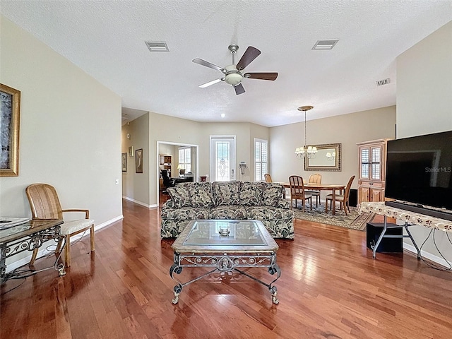 living room featuring visible vents, a textured ceiling, and wood finished floors