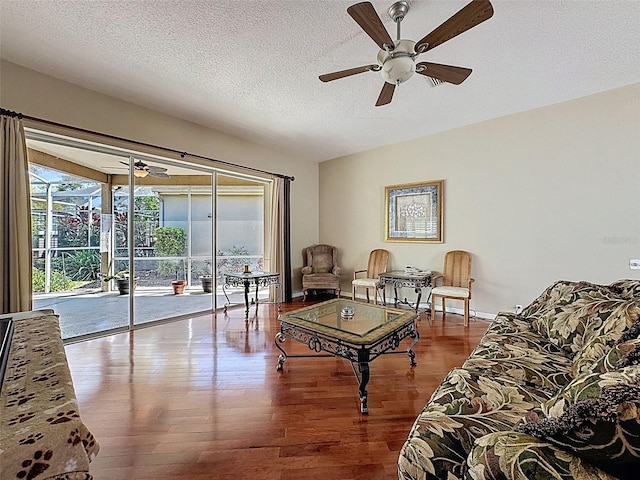 living area featuring ceiling fan, a textured ceiling, baseboards, and wood finished floors