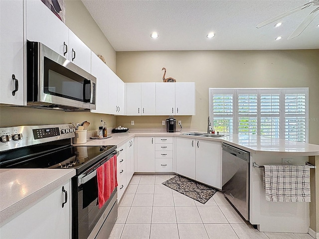 kitchen with a sink, appliances with stainless steel finishes, a peninsula, light countertops, and light tile patterned floors