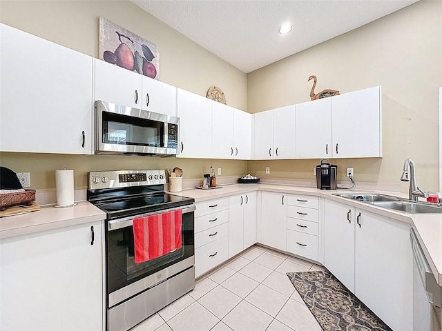 kitchen featuring light tile patterned flooring, a sink, light countertops, white cabinets, and appliances with stainless steel finishes