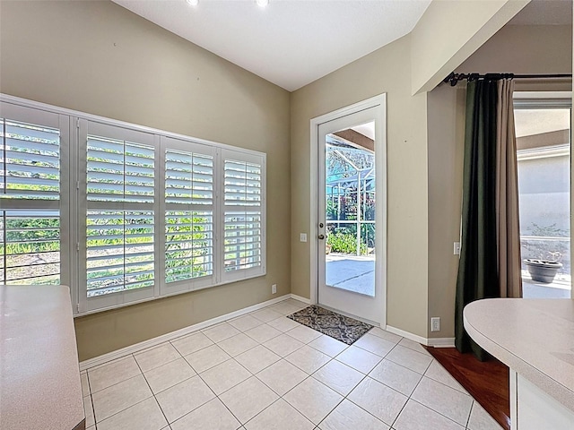 doorway featuring a wealth of natural light, baseboards, and light tile patterned floors