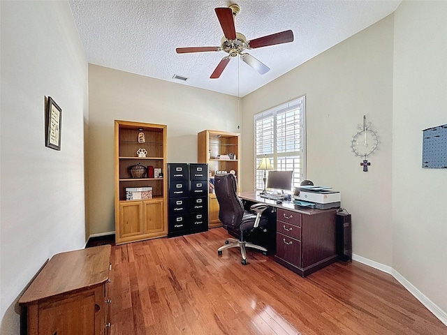 office space with visible vents, baseboards, light wood-style floors, and a textured ceiling