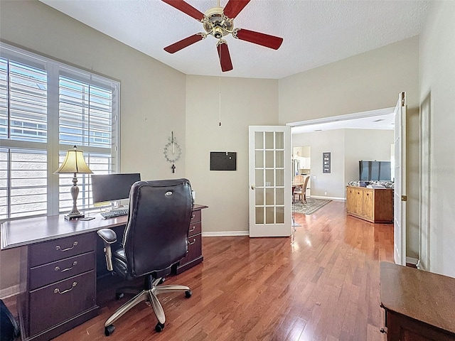 office space with french doors, a textured ceiling, baseboards, and wood finished floors