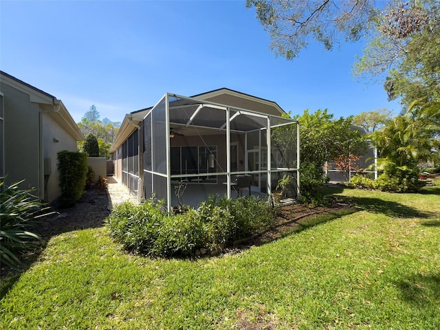 rear view of house featuring a yard, glass enclosure, and a ceiling fan