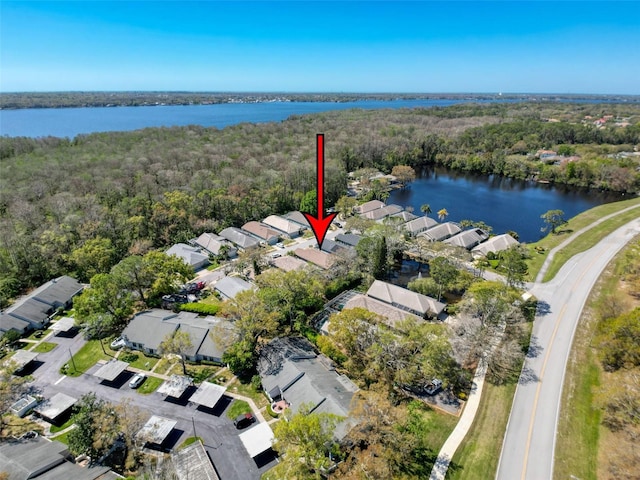 aerial view featuring a wooded view, a water view, and a residential view