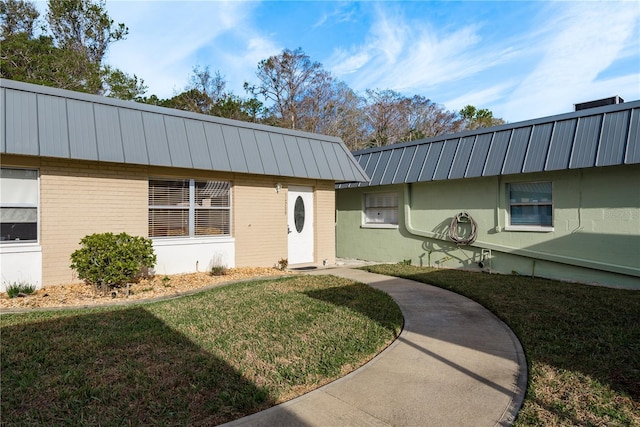 exterior space featuring brick siding and a front yard