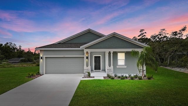 craftsman-style home with stucco siding, driveway, a front lawn, an attached garage, and a shingled roof