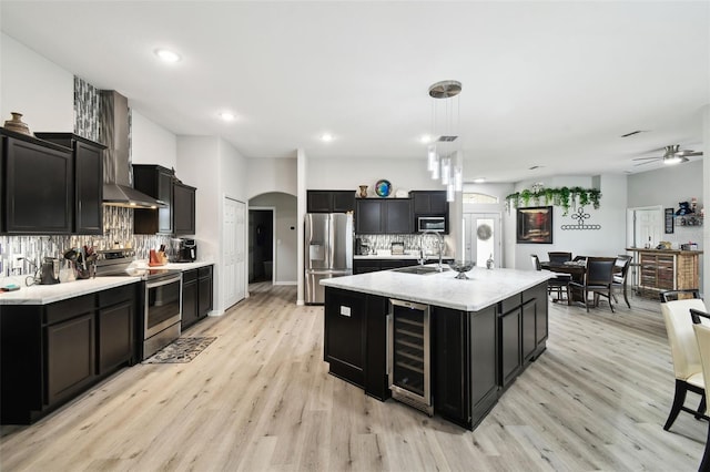 kitchen featuring dark cabinets, stainless steel appliances, arched walkways, and beverage cooler