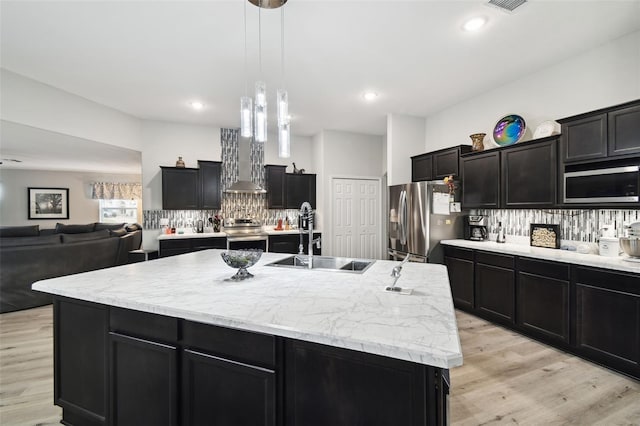 kitchen with backsplash, dark cabinets, appliances with stainless steel finishes, and a sink