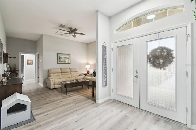 foyer entrance with ceiling fan, french doors, baseboards, and light wood-style flooring