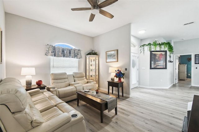 living room featuring a ceiling fan, visible vents, baseboards, and light wood-type flooring