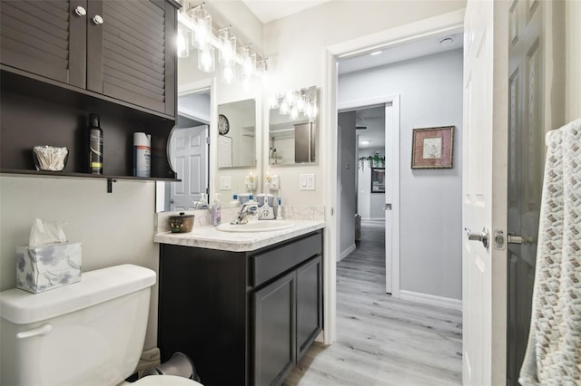 bathroom featuring vanity, toilet, wood finished floors, and baseboards