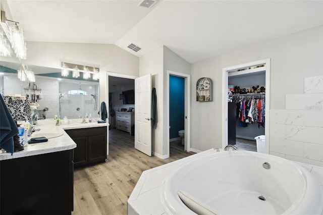 bathroom with vanity, a bath, visible vents, vaulted ceiling, and toilet