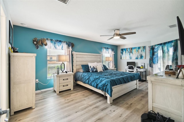 bedroom with visible vents, multiple windows, a ceiling fan, and light wood finished floors