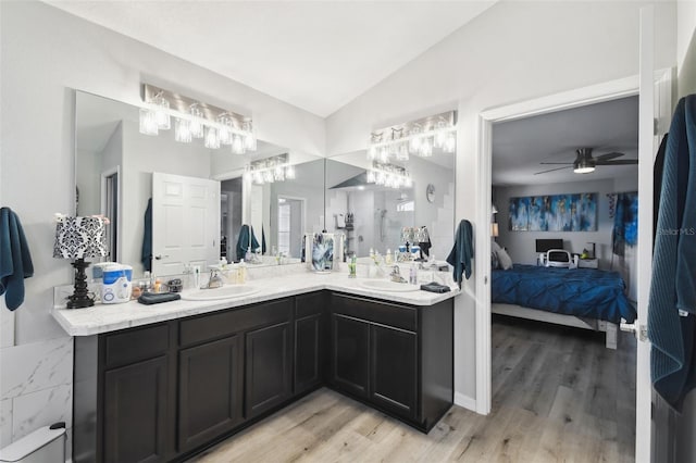 bathroom featuring vaulted ceiling, ensuite bath, wood finished floors, and a sink